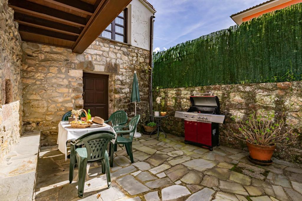 eine Terrasse mit einem Tisch, Stühlen und einem Grill in der Unterkunft La Casina del rincón in Mestas de Con