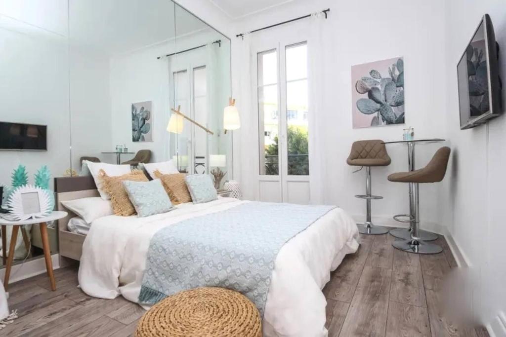 une chambre blanche avec un grand lit et une fenêtre dans l'établissement MIRAMAR-Studio tout confort sur la croisette, à Cannes