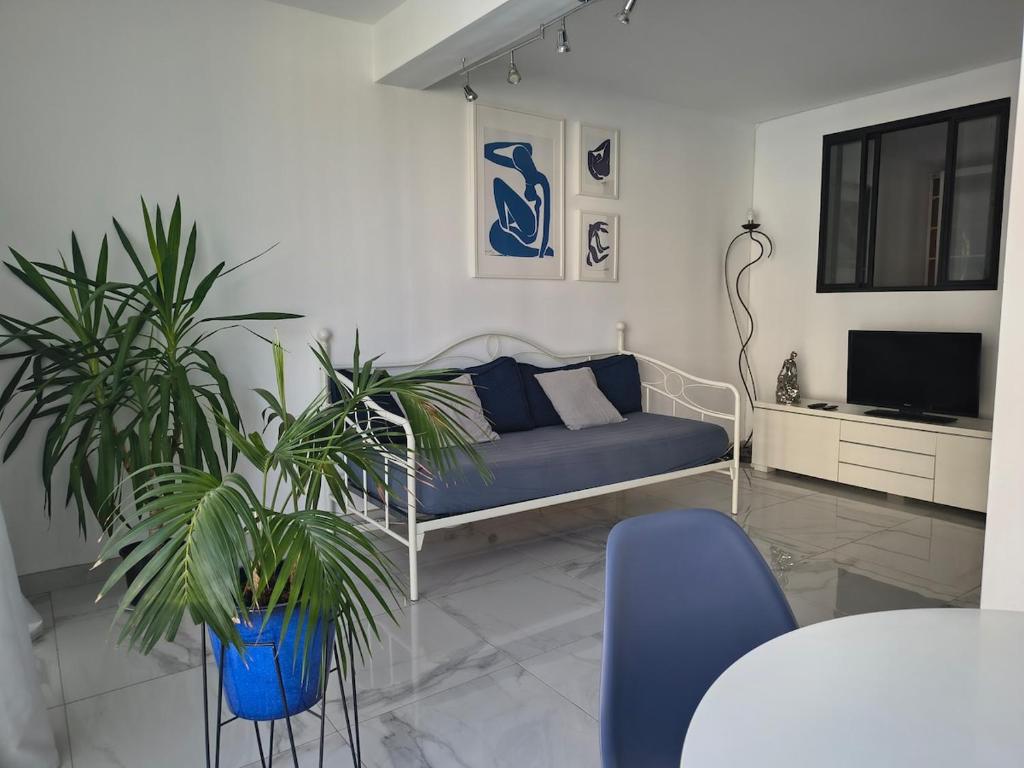 un salon avec un canapé bleu et deux plantes dans l'établissement Appartement bord de mer, à La Grande Motte