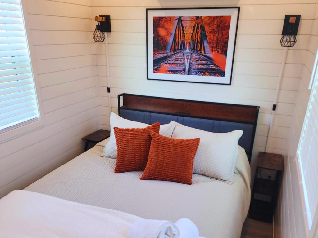 a bedroom with a bed with orange and white pillows at Barossa Valley Station Patio 1br Downtown in Fredericksburg