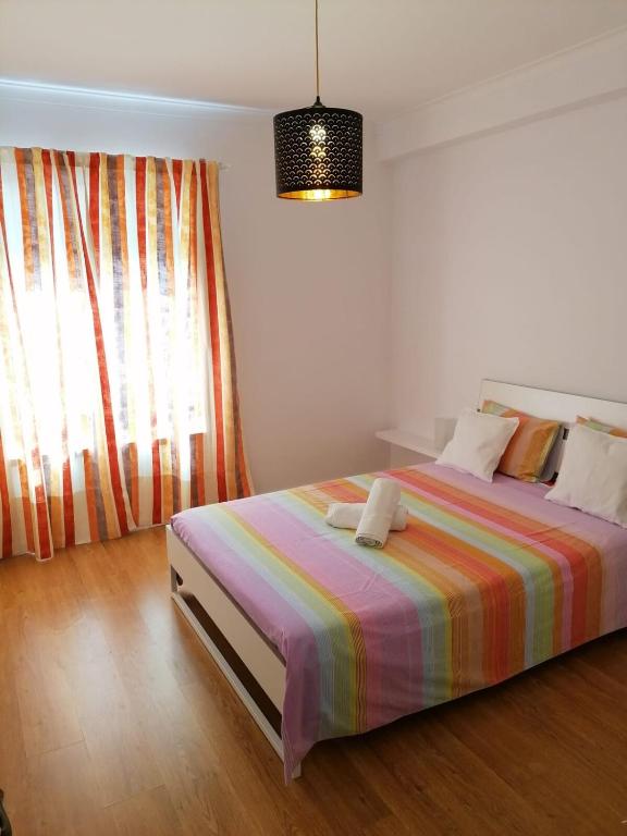 a bedroom with a bed with a colorful striped blanket at Casa acolhedora in Ponte da Barca