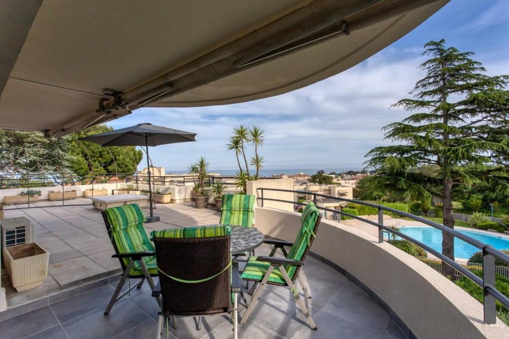 d'un balcon avec une table, des chaises et une piscine. dans l'établissement LES ANGES -F2 Appartement, terrasse vue mer, piscine, wifi, à Villeneuve-Loubet