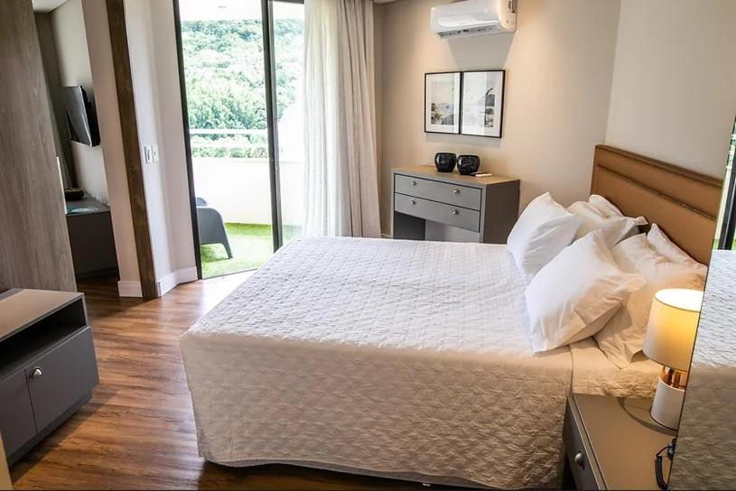 een slaapkamer met een groot wit bed en een raam bij Apto Studio Hotel Praia Brava in Florianópolis
