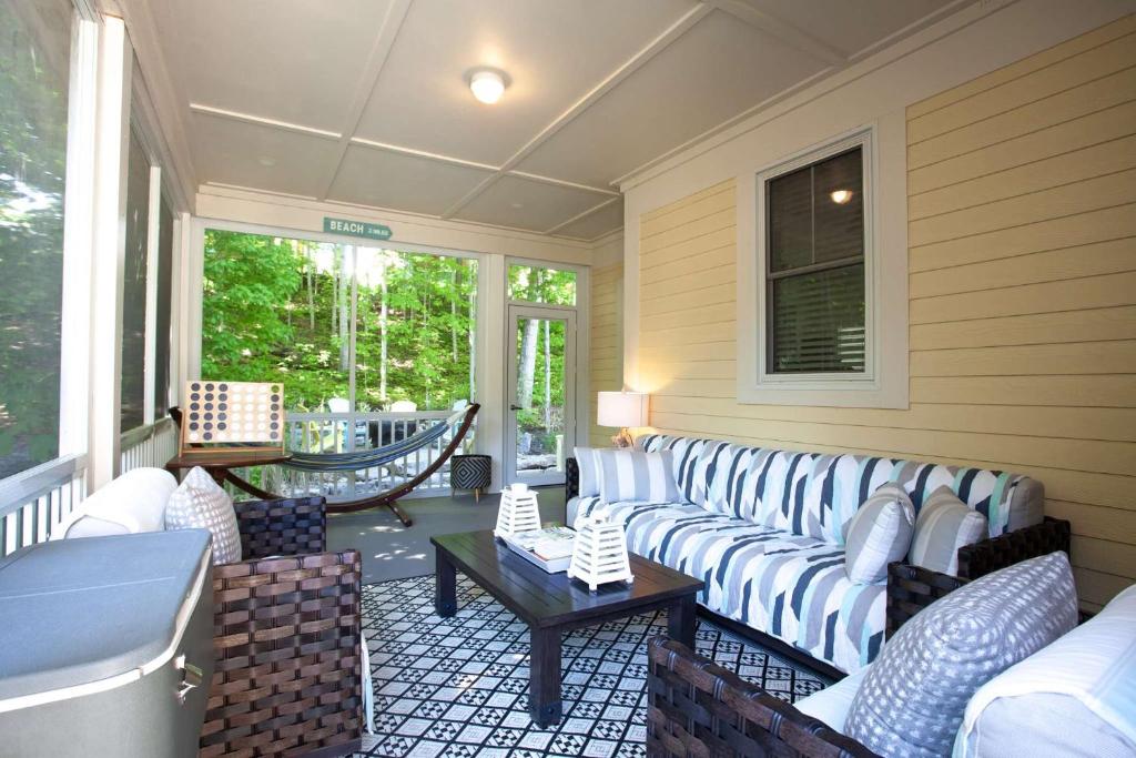 a screened in porch with couches and a table at The Spring Peeper - 28 Hollow in Cherry Valley
