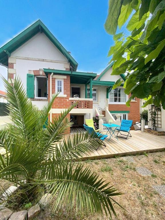 une maison avec une terrasse et deux chaises dans l'établissement Résidence 05025-lacanau Ocean - Magnifique Canaulaise typique 5 chambres, 10 personnes à Lacanau océan MAE-0561, à Lacanau