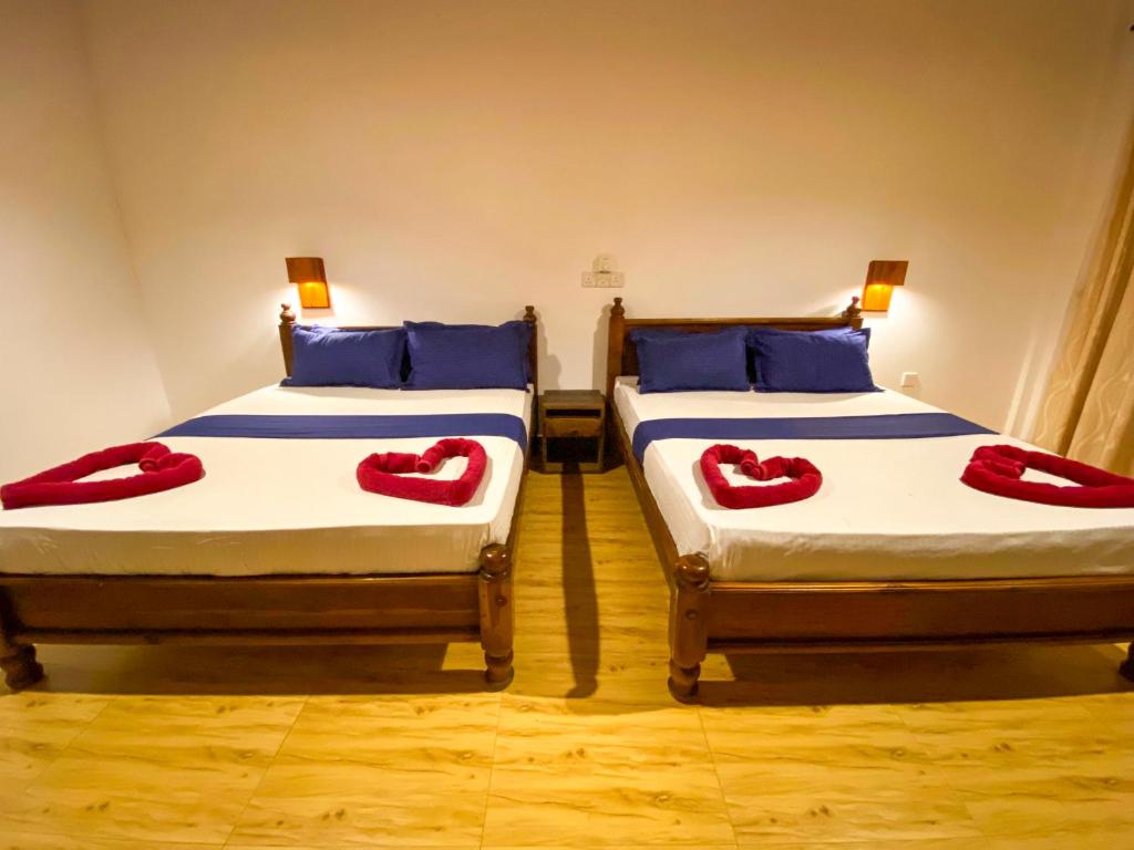 two beds in a room with red pillows on them at Oasis Bay - Arugam Bay in Arugam Bay