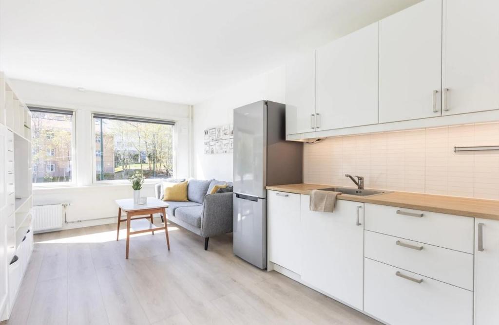 a kitchen with white cabinets and a table and a chair at Modern apartment ONLY 5 minutes from City centre in Bergen
