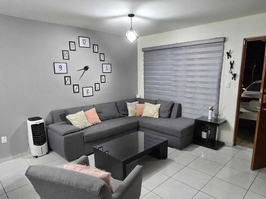 a living room with a couch and a clock on the wall at Pozos Comfort House in San Luis Potosí