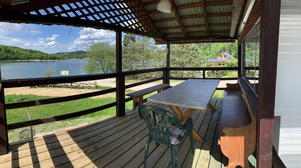 une terrasse avec une table, un banc et un lac dans l'établissement 50m od Jeziora Holender, à Zawóz