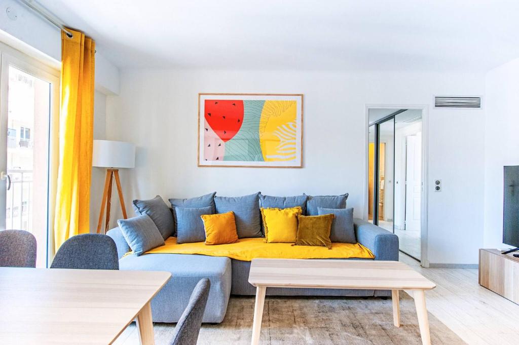 un canapé bleu avec des coussins jaunes dans un salon dans l'établissement MILADY-Perle neuve, wifi, climatisée, Centre d'Antibes au calme, à Antibes
