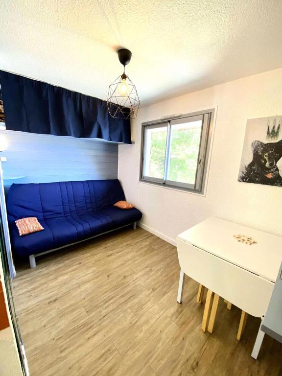 un salon avec un canapé bleu et une table dans l'établissement Résidence Kandahar - Agréable studette au centre de la station MAE-5461, à Vénosc