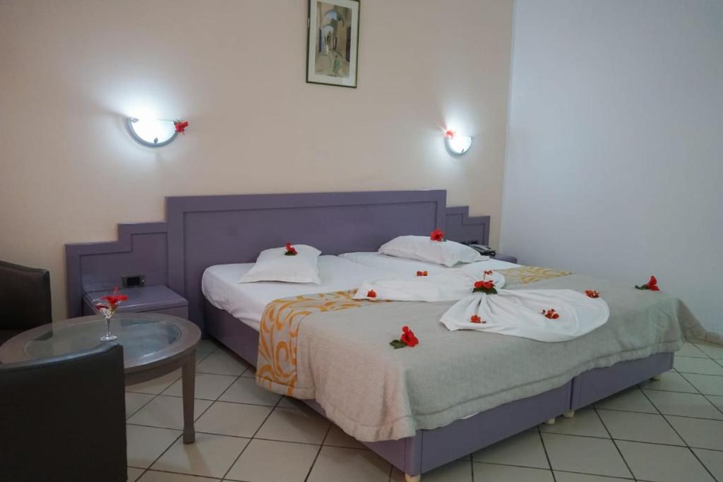 una camera con due letti con fiocchi rossi sopra di Hôtel Excel KHIMA a Yasmine