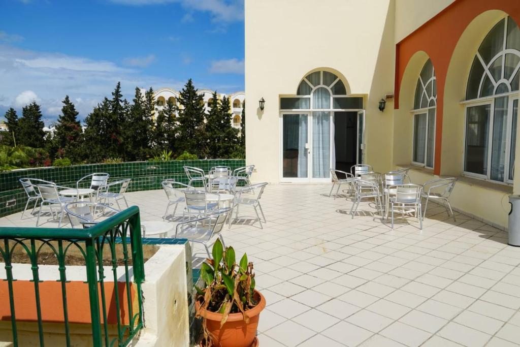 un patio con tavoli e sedie in un edificio di Hôtel Excel KHIMA a Yasmine