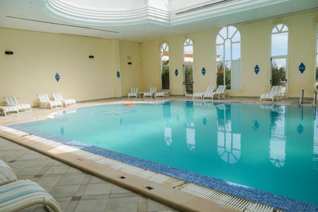 una grande piscina in una grande stanza con sedie di Hôtel Excel KHIMA a Yasmine