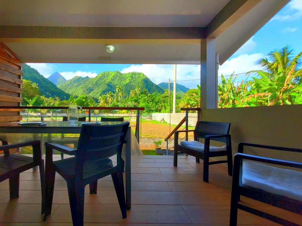 balcone con tavolo, sedie e vista sulle montagne. di Teahupo'o Lodge Tahiti - Studio Tropical - climatisé - entre randonnées et activités nautiques a Teahupoo