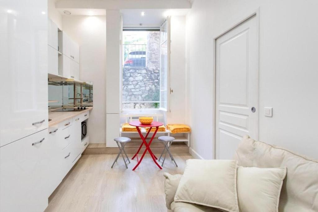 une cuisine blanche avec une table rouge dans une pièce dans l'établissement ROSIE-Charmant Cocon à Beausoleil, aux Portes de Monaco, à Beausoleil