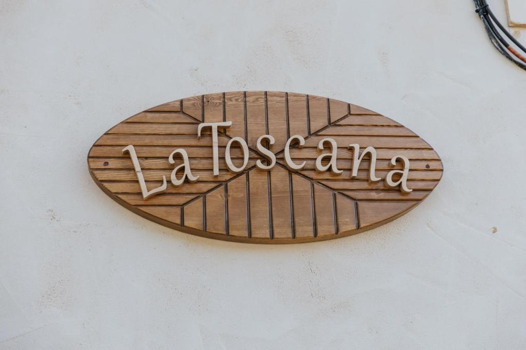 Un cartel de madera en una pared con la palabra laoscemia en La Toscana Casa Rural piscina ,parking ,barbacoa, en Jadraque