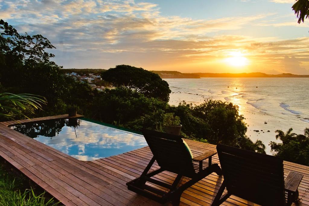 a deck with two chairs and the ocean at sunset at Pipa Villa ByBeck - Praia do Amor - Casa inteira in Pipa