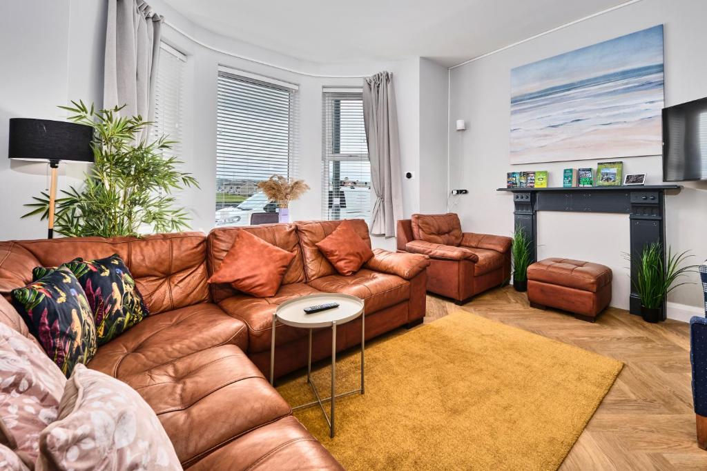 a living room with a brown leather couch and a fireplace at Dunluce Green 1 - Portrush by the Sea in Portrush