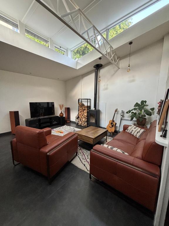 un salon avec deux canapés en cuir marron et un piano dans l'établissement Atypical house near Paris & Disney, à Champigny-sur-Marne