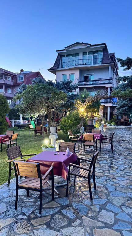 a group of tables and benches with a building in the background at Villa Enhalon in Struga