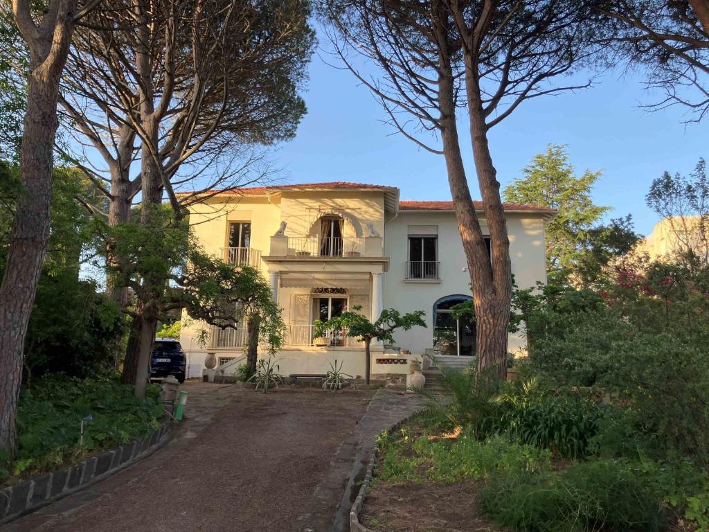une maison jaune avec des arbres devant elle dans l'établissement Grande Villa bord de mer, face au port Santa Lucia, à Saint-Raphaël