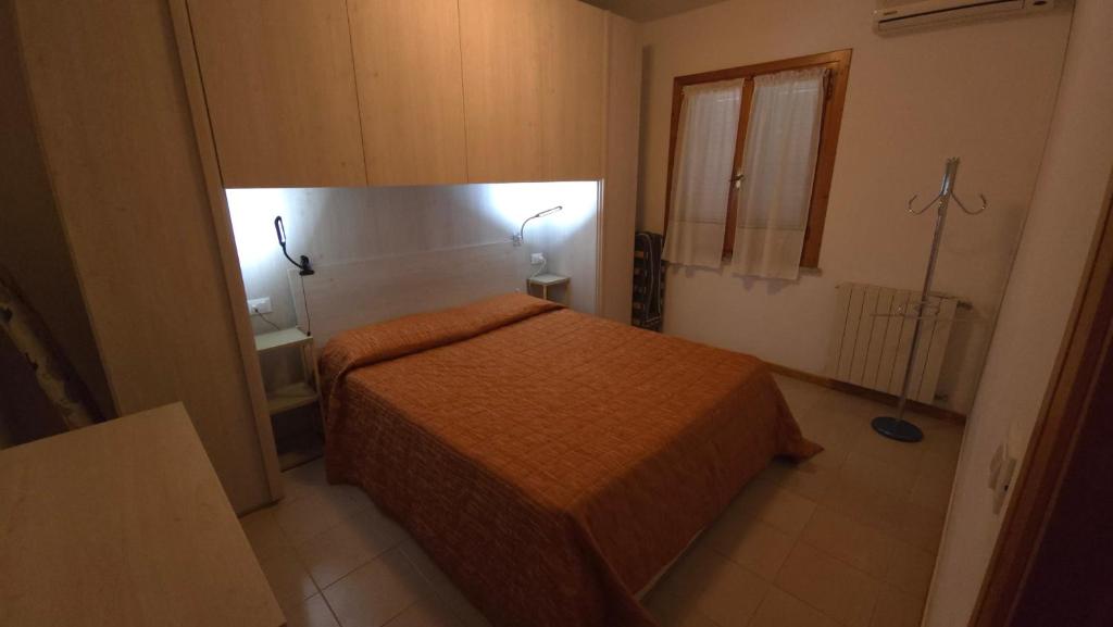 mały pokój z łóżkiem i oknem w obiekcie Appartamento verde w mieście Porto Azzurro