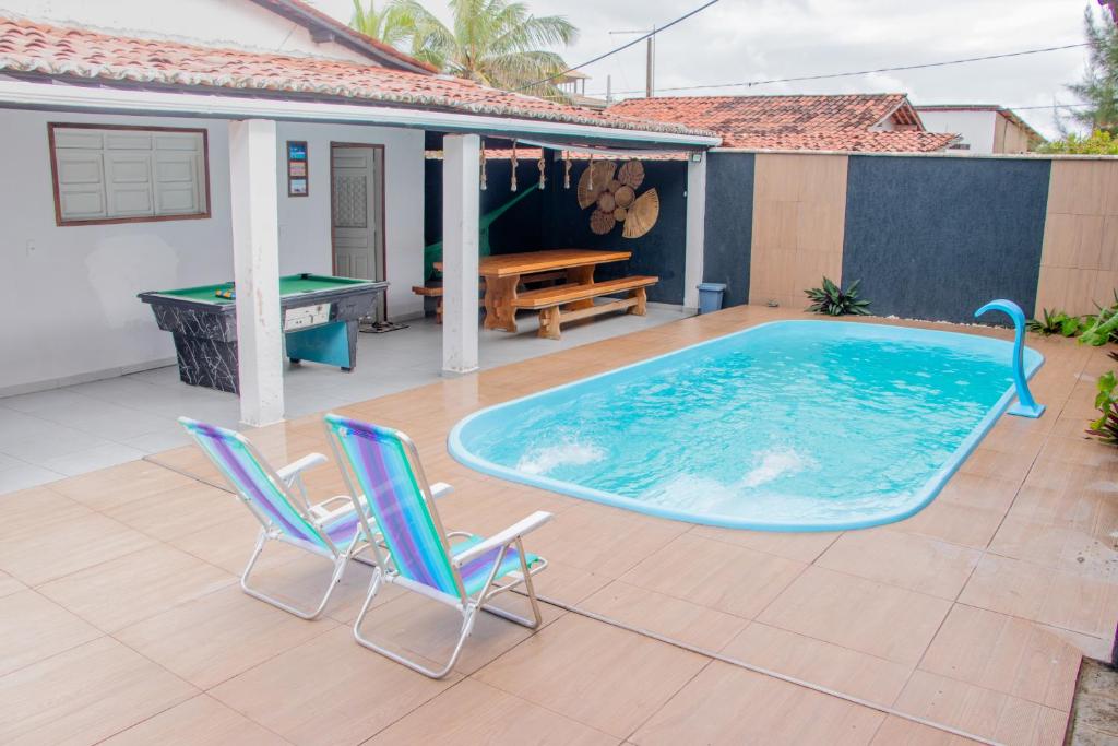 a pool with two chairs and a ping pong table at Casa da Prainha Baia da Traição Pb Piscina com hidromassagem a 30m do mar in Baía da Traição