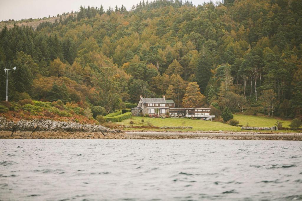 a house on a hill next to the water at Loch View House in Kilfinan