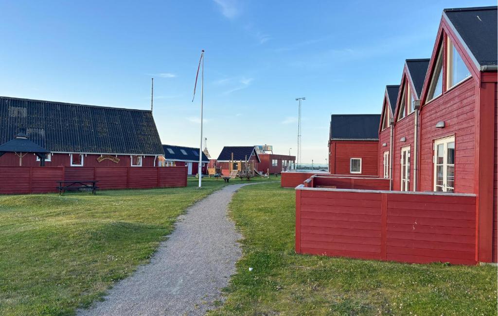 un edificio rosso con una strada sterrata accanto a un campo di 3 Bedroom Lovely Home In Strandby a Strandby