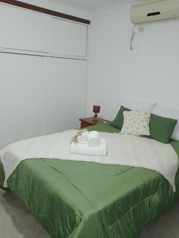 a bedroom with a bed with a green comforter at La Ñata in Tandil