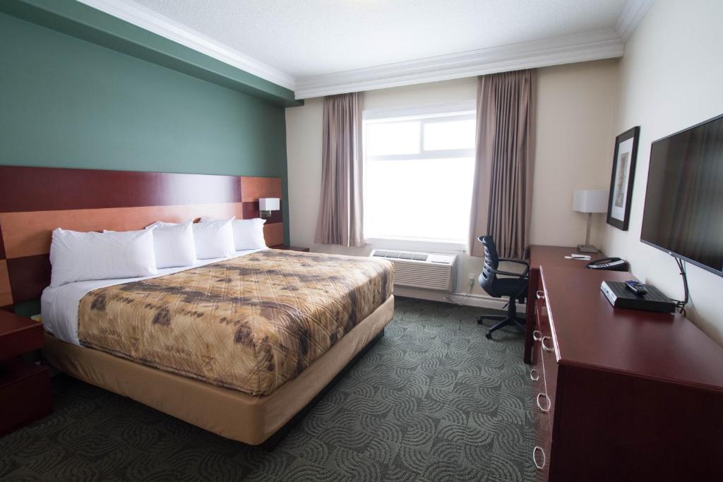 a hotel room with a bed and a desk and a television at Nova Inn Manning in Manning