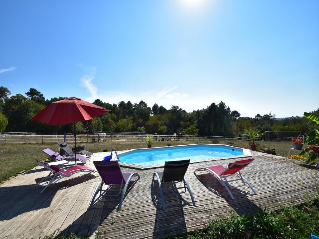 - une piscine avec des chaises et un parasol sur une terrasse en bois dans l'établissement Holiday Home Montferrand Pool & Terrace, cleaning included, à Montferrand-du-Périgord