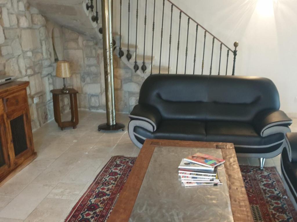 un salon avec un canapé noir et une table dans l'établissement Holiday Home in Montfrin with Private Pool, cleaning included, à Montfrin