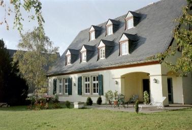 ein großes weißes Haus mit einem Gameradach in der Unterkunft Gut Hermannsberg, Gästehaus in Niederhausen