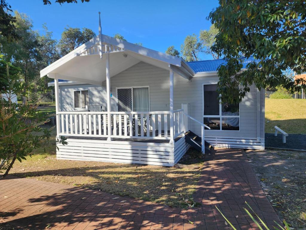 a white house with a porch and a driveway at NRMA Broulee Holiday park in Broulee