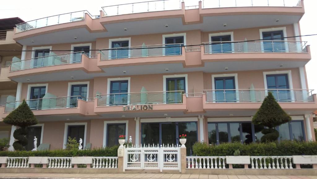 a pink building with a white fence in front of it at Enalion in Olympic Beach