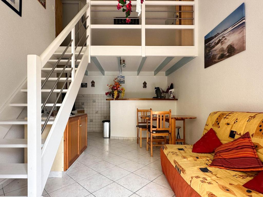 Il comprend un salon avec un canapé et une cuisine avec un escalier. dans l'établissement Maison familiale proche plage - La Palmyre - FR-1-705-101, aux Mathes