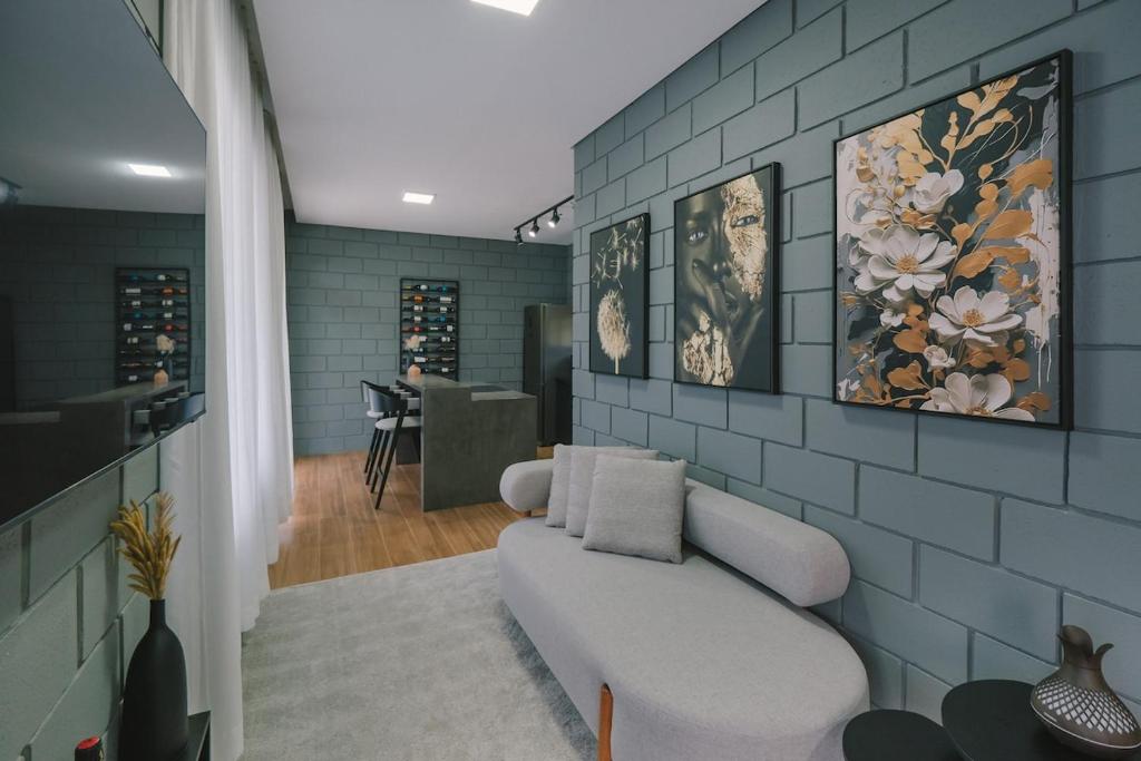 a living room with a white couch and a tile wall at Blockhaus - hosting with purpose in Rancho Queimado