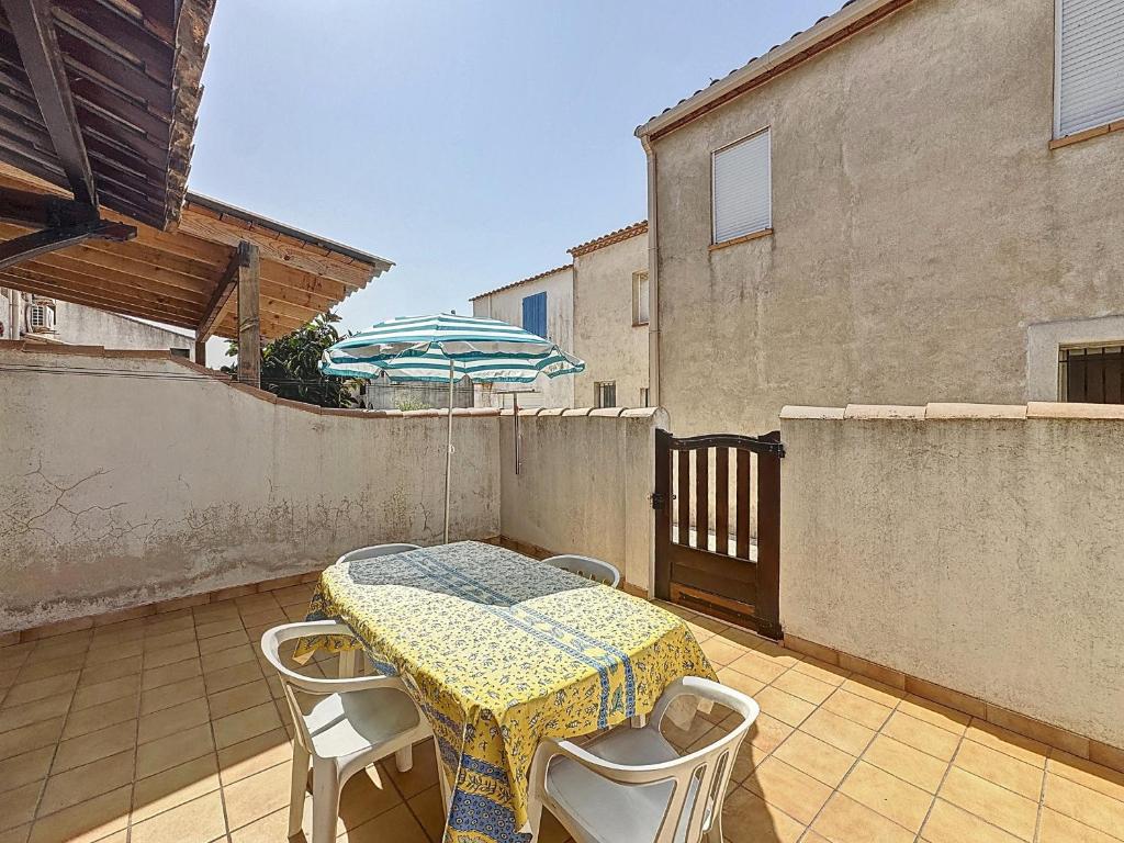 - une table et des chaises sur une terrasse avec un parasol dans l'établissement Appartement pour 4 pers. avec cour privative aux Saintes-Maries-de-la-Mer - FR-1-475-210, à Saintes-Maries-de-la-Mer