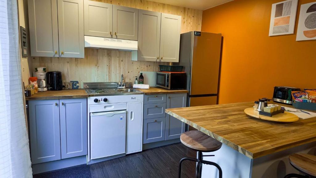 a kitchen with white cabinets and a refrigerator at La Cabane Sereine - Pause Nordique & simplicite in Rouyn-Noranda