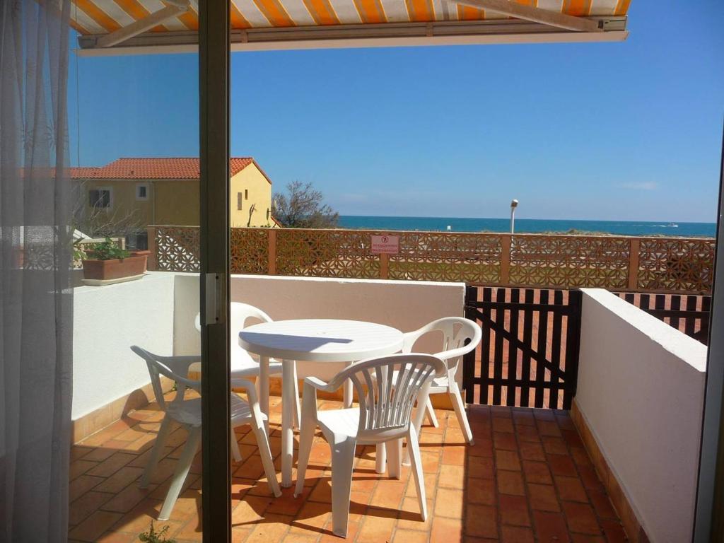 un patio avec une table et des chaises sur un balcon dans l'établissement Studio Cabine RDC, 4 Pers, Accès Direct Plage - FR-1-782-78, au Barcarès