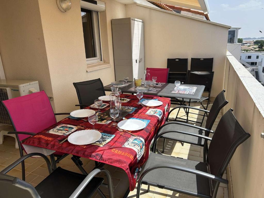 une table avec des assiettes et des verres sur un balcon dans l'établissement Appt 2 pièces climatisé pour 4 pers, Le Grau-du-Roi - FR-1-250-314, au Grau-du-Roi