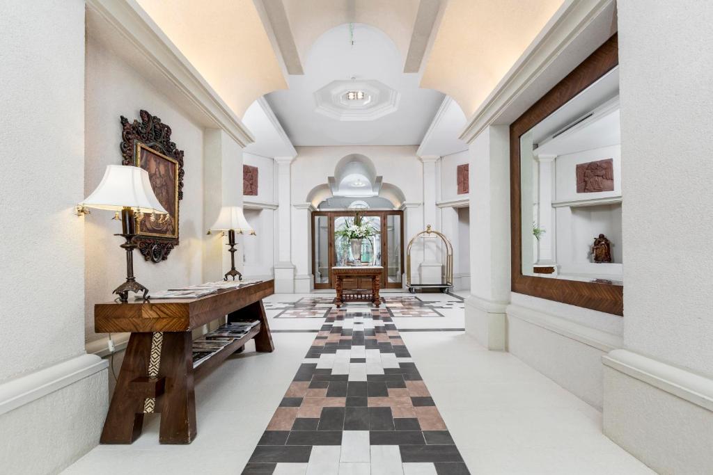 a hallway with a piano and a checkerboard floor at La Mision Hotel Boutique in Asunción