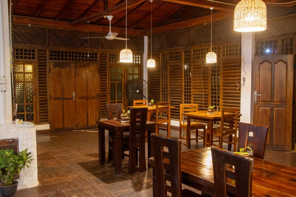 a dining room with wooden tables and chairs and lights at Oasis Bay - Arugam Bay in Arugam Bay