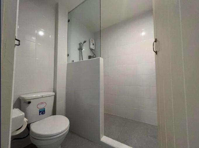 a white bathroom with a toilet and a shower at Niagara Hotel in Bangkok