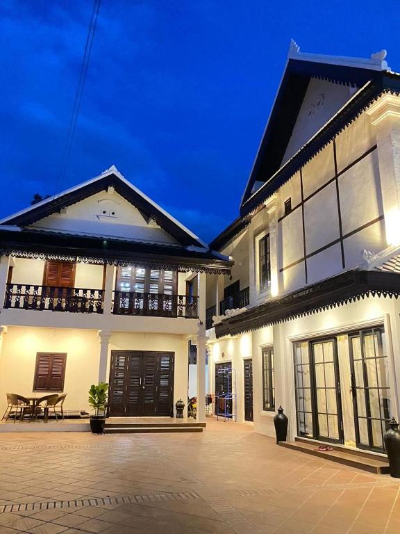 a large white house with a patio in front of it at Onson De Boutique Hotel in Luang Prabang