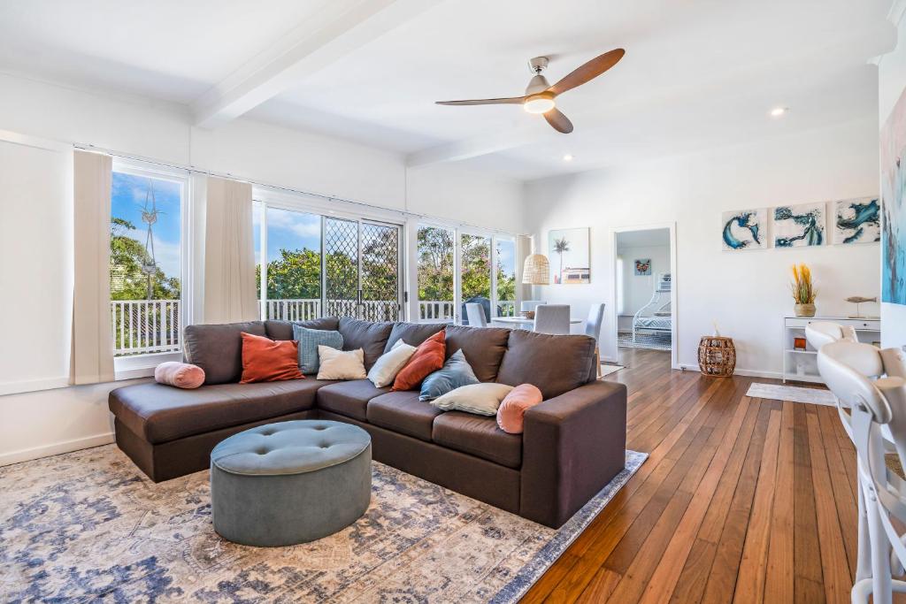 a living room with a brown couch and a ceiling fan at Yaringa -13 Seaview Street SWR in South West Rocks