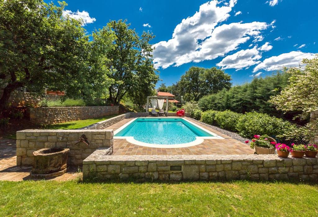 a swimming pool in a yard with a stone wall at Villa Loren in Avber