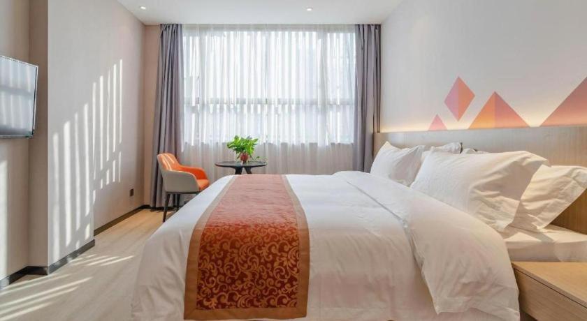 ein Schlafzimmer mit einem großen weißen Bett und einem Fenster in der Unterkunft Borrman Hotel Hefei Yaohai Wanda Linquan East Road in Hefei